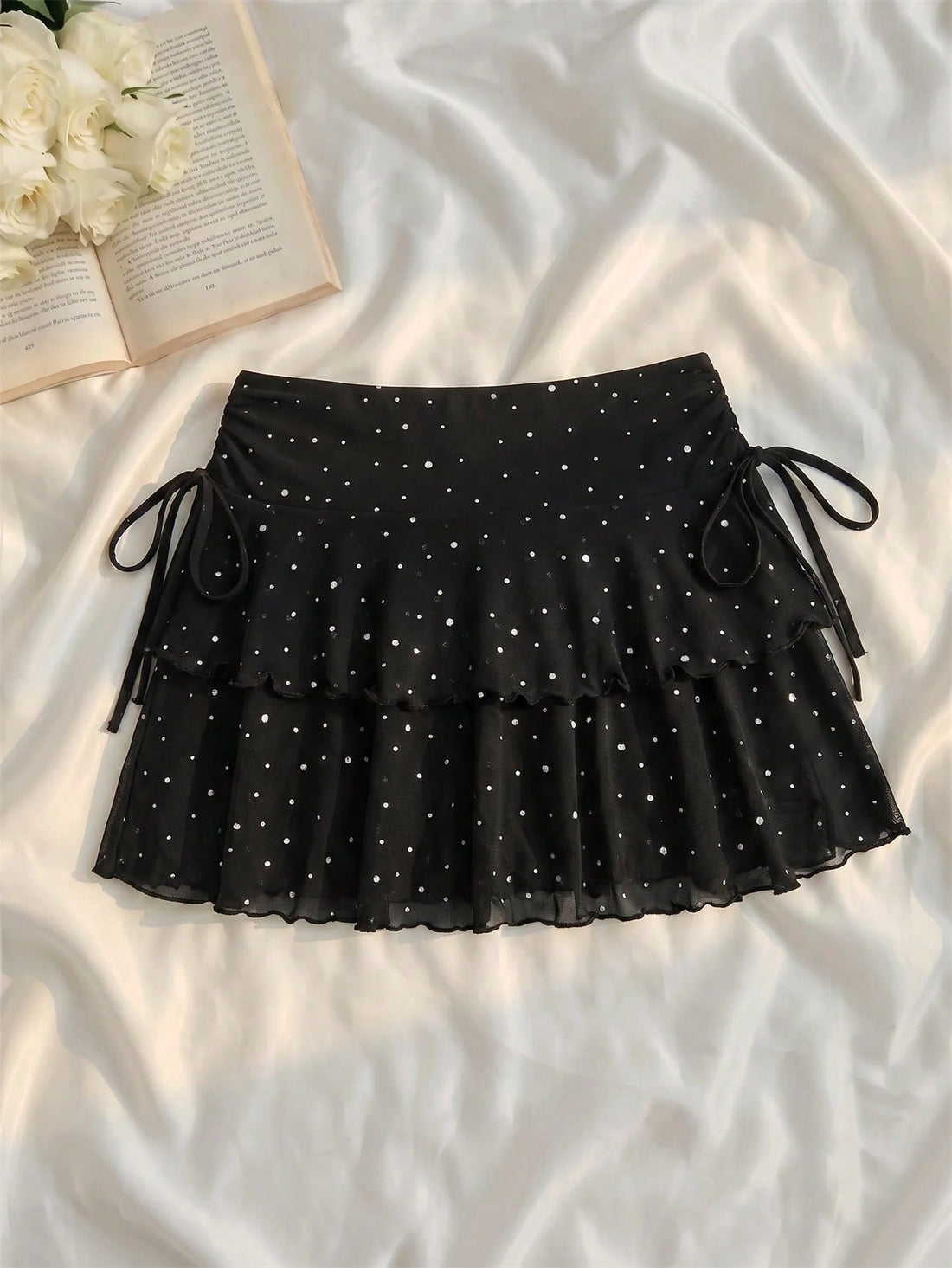 Black polka dot mini skirt featuring tiered ruffle hem design on loose fit knitted fabric.