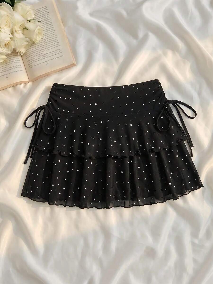 Black polka dot mini skirt featuring tiered ruffle hem design on loose fit knitted fabric.