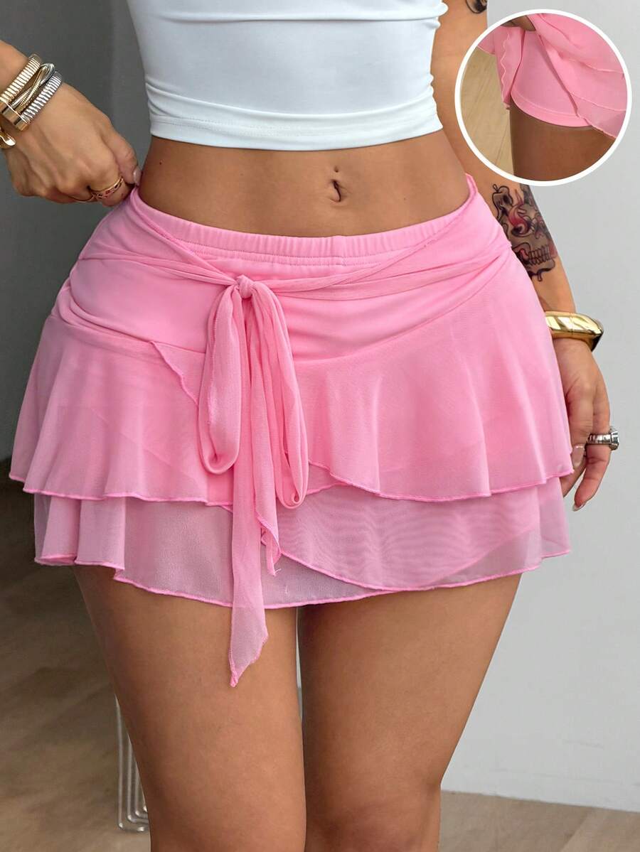 Black low waist tiered mini skirt featuring a ruffle hem and ring accent detail on knitted stretch fabric for women.