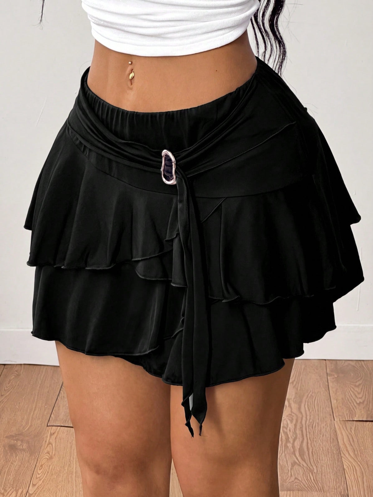 Black low waist tiered mini skirt featuring a ruffle hem and ring accent detail on knitted stretch fabric for women.