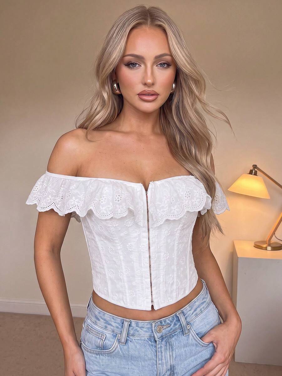 Women’s white corset top with embroidered ruffle trim, off-shoulder neckline, lace-up details, front hook closure, and sleeveless crop fit.