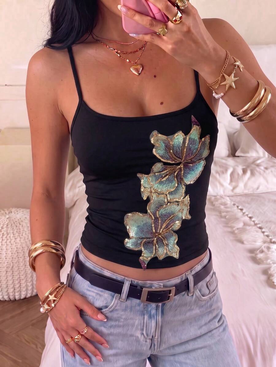 Women's black floral backless camisole top featuring spaghetti straps and front ring detail on knitted stretch fabric.