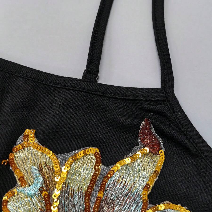 Women's black floral backless camisole top featuring spaghetti straps and front ring detail on knitted stretch fabric.