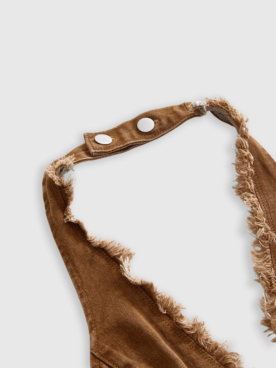 Women's denim halter crop top featuring a backless design, asymmetrical hem, single-breasted front, and lettuce trim.