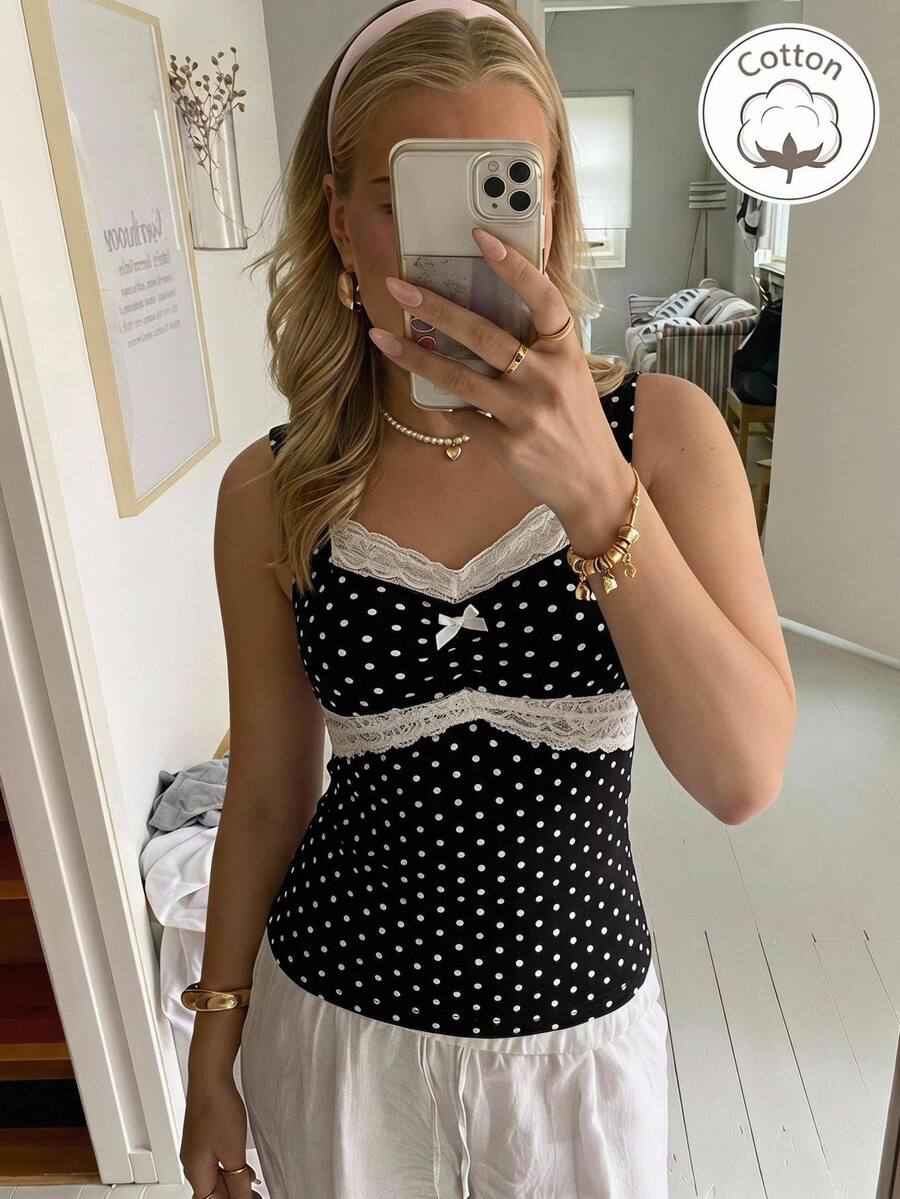 Black and white polka dot knit camisole tank top featuring delicate contrast lace trim, a cute bow accent at the sweetheart neckline, and slender shoulder straps.