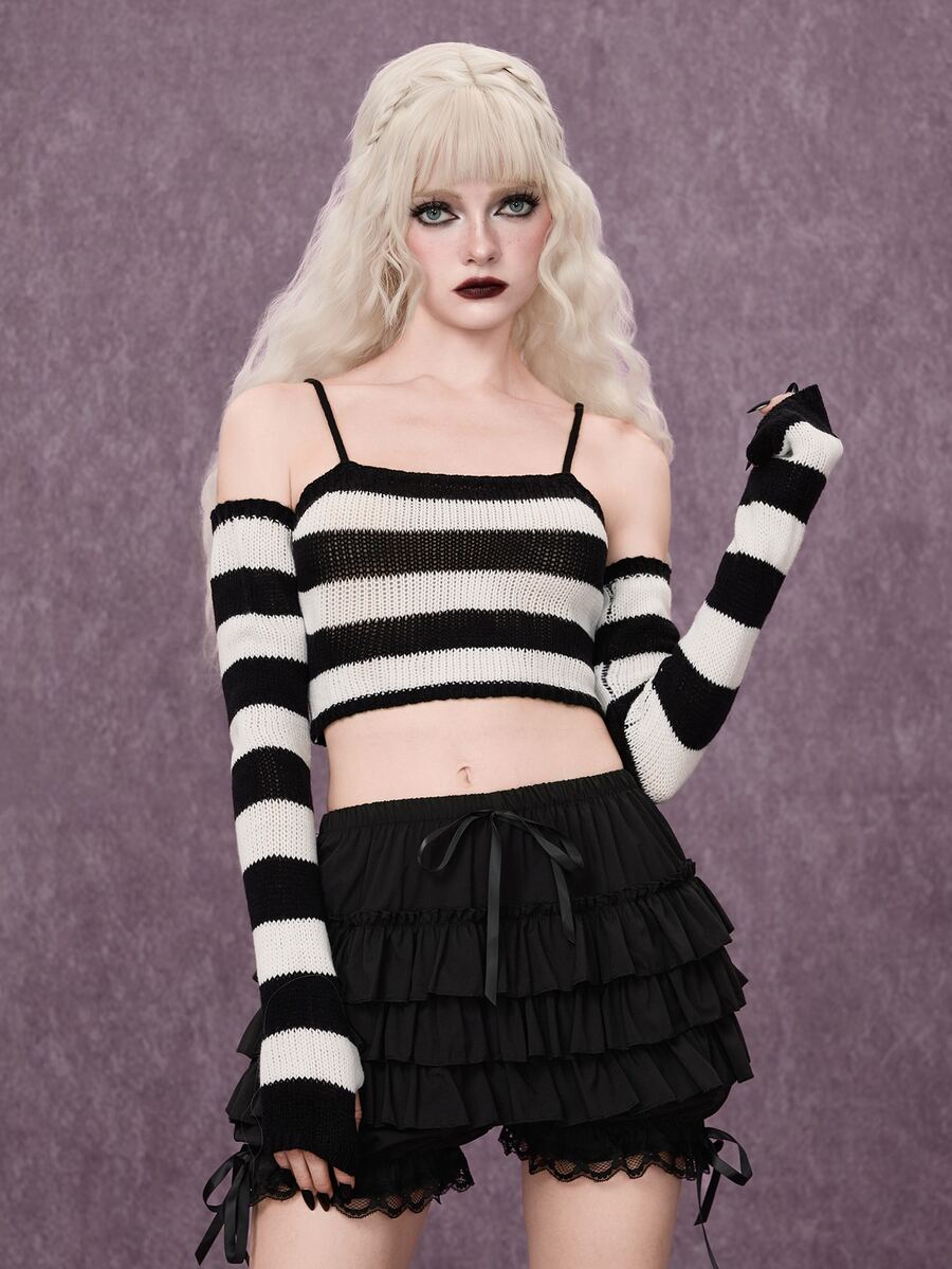 Women wearing a black and white striped camisole knit crop top with spaghetti straps and extra-long cold shoulder sleeves.