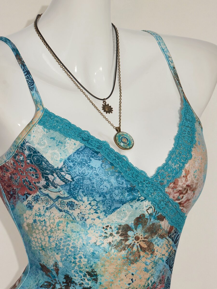 Women's blue fitted camisole top with contrast lace patchwork print, backless asymmetrical hem, and spaghetti straps.