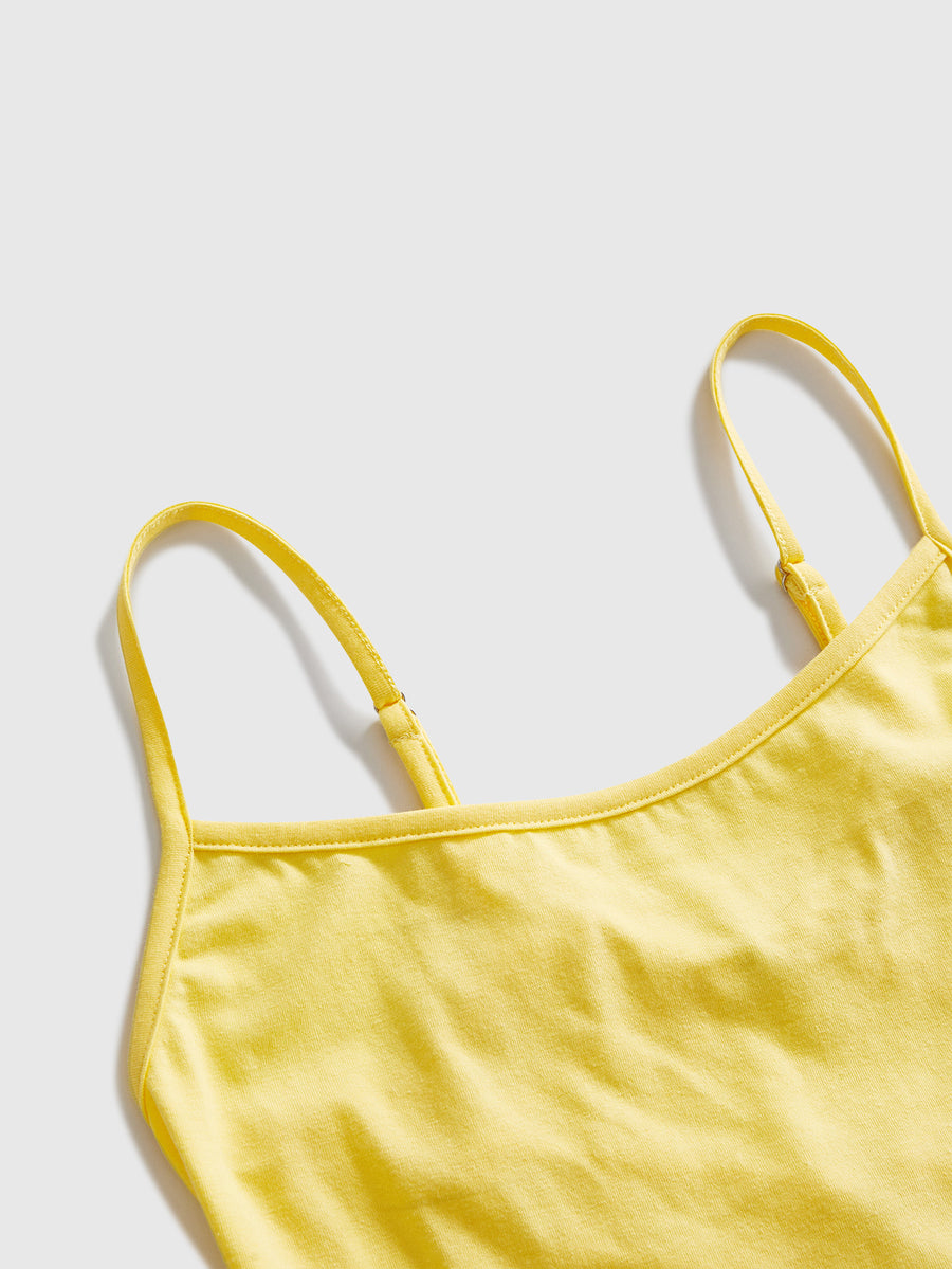Woman wearing a black backless halter tank top with criss-cross details and textured knit fabric