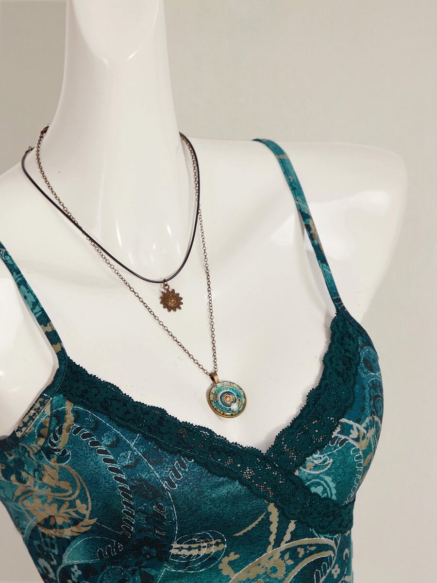 Women's blue fitted camisole top with contrast lace patchwork print, backless asymmetrical hem, and spaghetti straps.