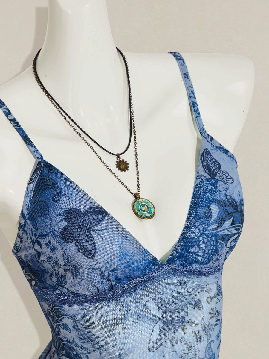 Women's burgundy floral graphic print mesh camisole top featuring an asymmetrical hem, backless cut, and spaghetti straps.