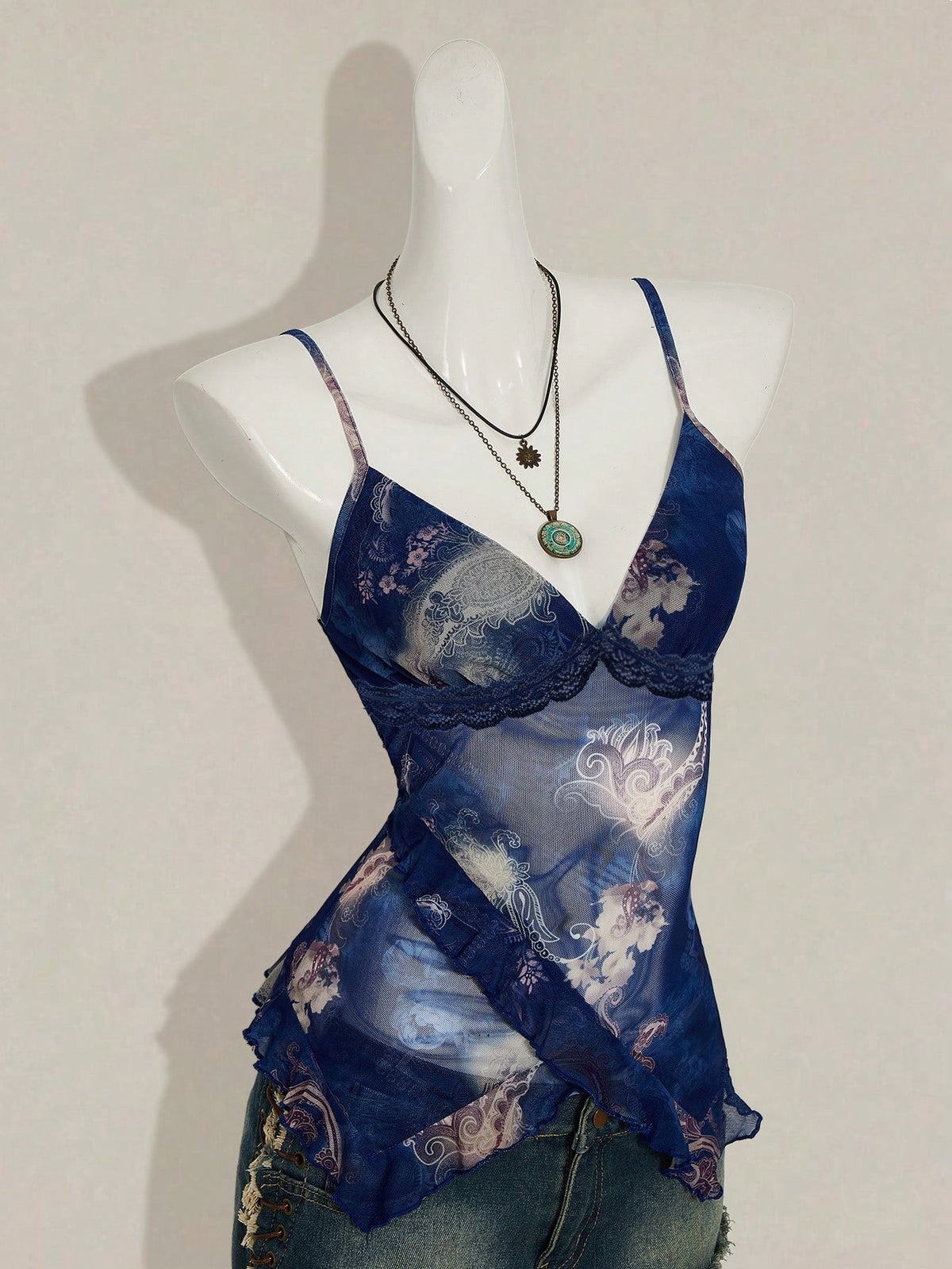 Women's burgundy floral graphic print mesh camisole top featuring an asymmetrical hem, backless cut, and spaghetti straps.