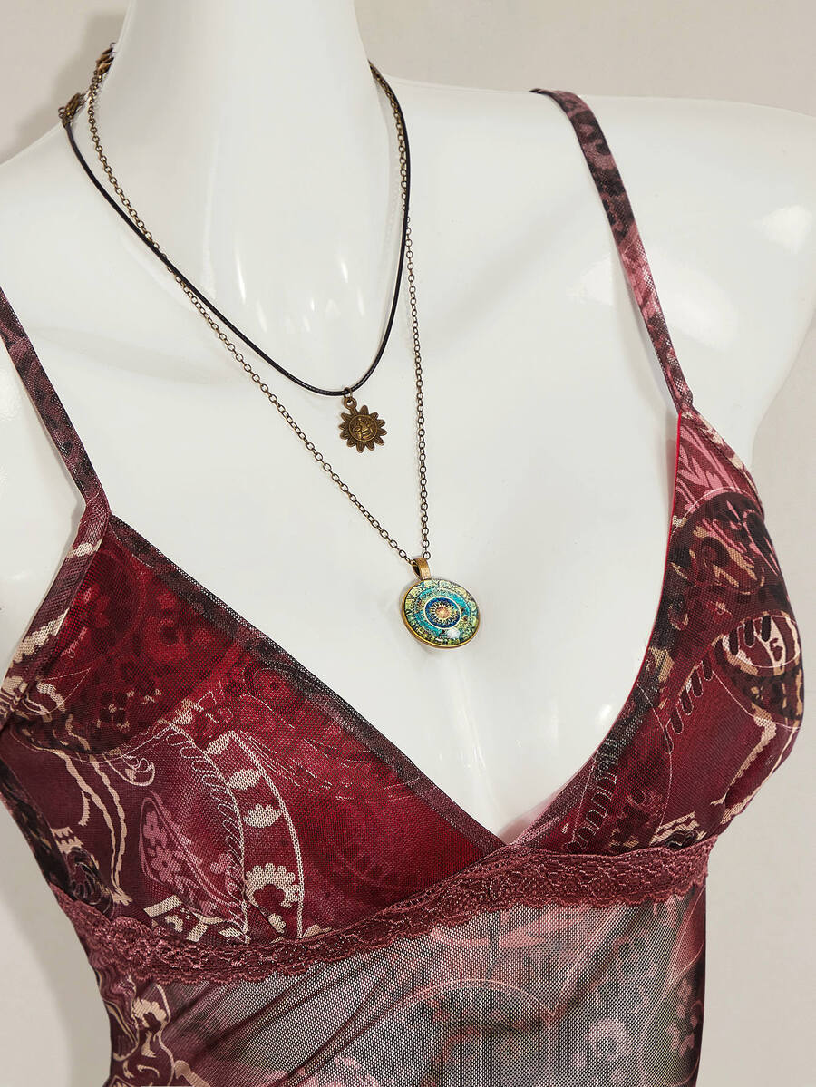 Women's burgundy floral graphic print mesh camisole top featuring an asymmetrical hem, backless cut, and spaghetti straps.