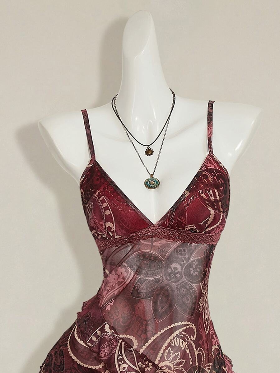 Women's burgundy floral graphic print mesh camisole top featuring an asymmetrical hem, backless cut, and spaghetti straps.