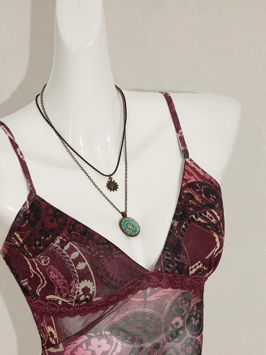 Women's burgundy floral graphic print mesh camisole top featuring an asymmetrical hem, backless cut, and spaghetti straps.