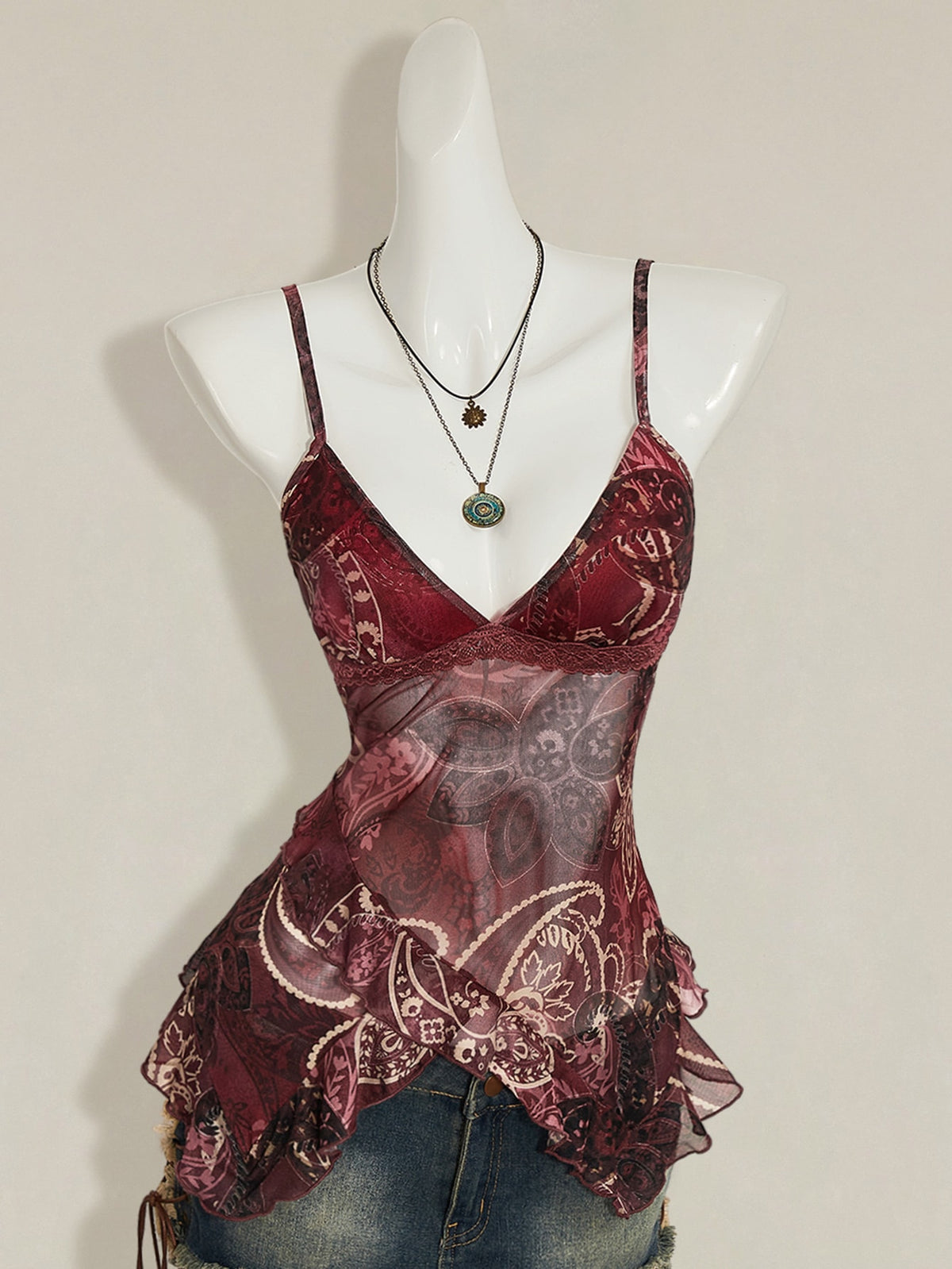 Women's burgundy floral graphic print mesh camisole top featuring an asymmetrical hem, backless cut, and spaghetti straps.