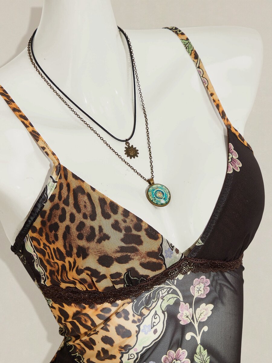 Women's burgundy floral graphic print mesh camisole top featuring an asymmetrical hem, backless cut, and spaghetti straps.