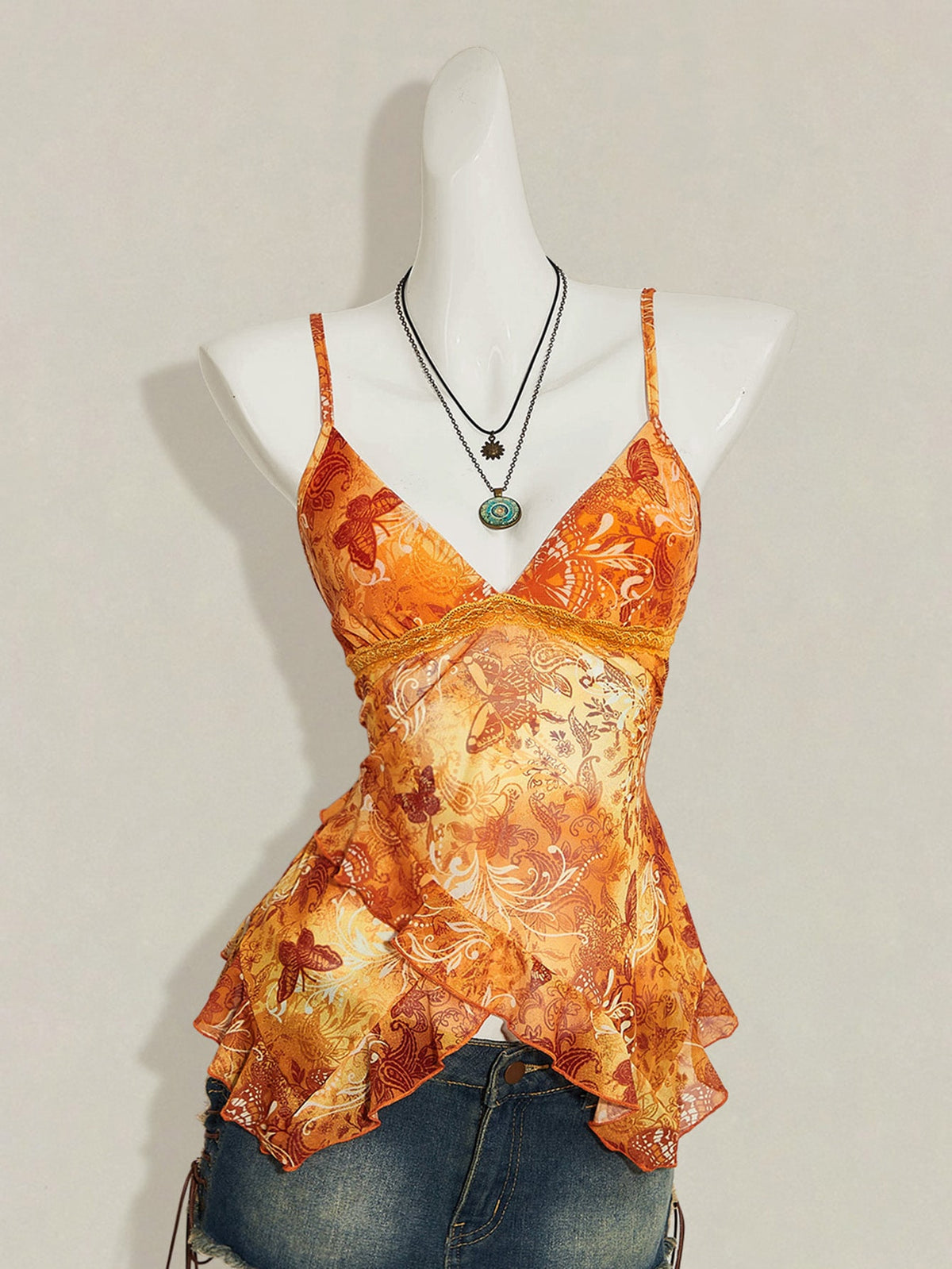 Women's burgundy floral graphic print mesh camisole top featuring an asymmetrical hem, backless cut, and spaghetti straps.