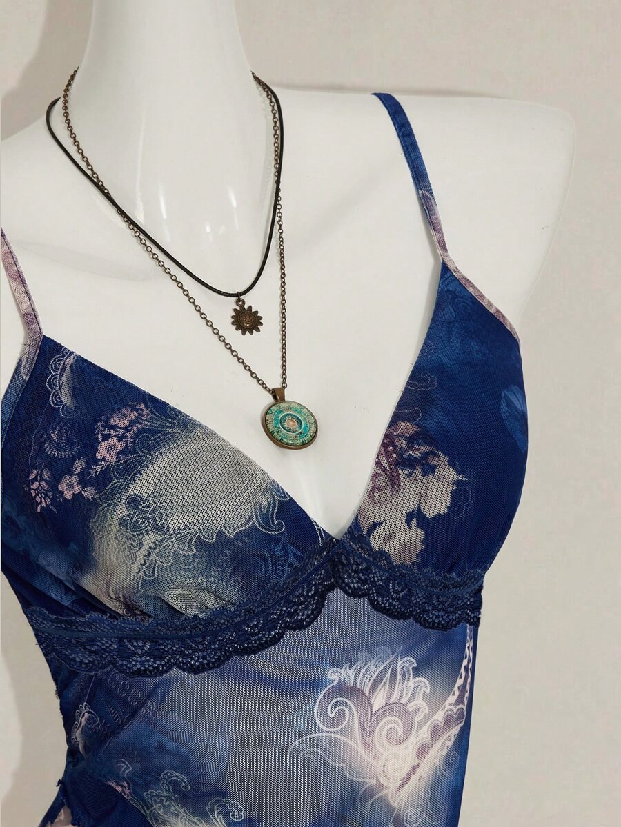 Women's burgundy floral graphic print mesh camisole top featuring an asymmetrical hem, backless cut, and spaghetti straps.