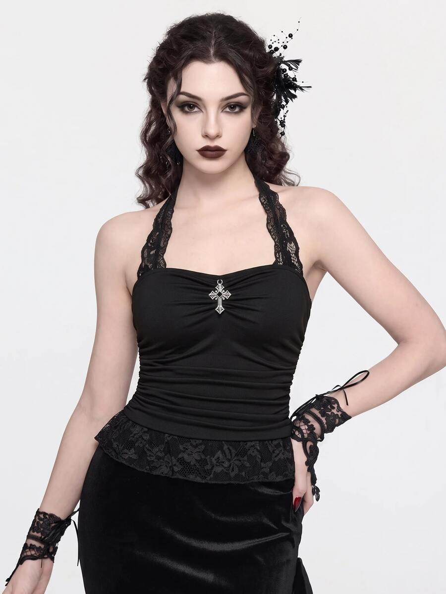 Front view of a women's black gothic Y2K halter crop top with contrast lace trim, ruched waist detail, cross accent, and tie-back backless design.